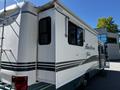 A 2000 Ford Motorhome with a white exterior and green accents featuring a slide-out section and a ladder on the rear