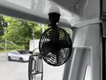 A small black circular fan mounted on the interior of a bus with three blades visible