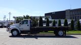 A white 2006 Ford F-650 flatbed truck parked with a long flatbed and no cargo