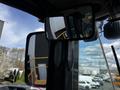 A 2006 John Deere 470G excavator with a focus on its side mirror reflecting the nearby environment