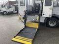 A yellow and black wheelchair lift is deployed from the rear of a 2018 Chevrolet Express van