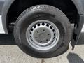 Close-up of a wheel and tire of a 2012 Mercedes-Benz Sprinter featuring a circular rim with multiple holes and a black tire with tread pattern