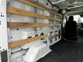 Interior of a 2023 Ford Transit van showing wooden panels attached to the walls and a single black seat in the front cabin area