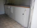 A 2004 Royal 18 Foot Office Trailer featuring a counter with a key lock cabinet and a white wall panel with a vent and electrical outlet