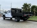A 2017 Ford F-450 Super Duty truck with a black flatbed and dual rear wheels parked at an angle showing the driver's side and rear view