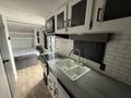 Interior of a 2022 Keystone Hideout RDWE 20RDWE camper featuring a kitchenette with a sink stove and microwave along with a bed area in the background