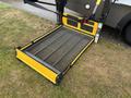 A yellow and black wheelchair lift platform for a 2020 Chevrolet Express with a textured surface and a foldable design