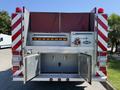 The rear view of a 1991 International 4600 fire truck featuring red lights reflective stripes and a compartment with open doors for storage