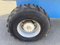 Close-up of a large tire from a 1997 Genie S-65 4X4 with a rugged tread and a metal rim showcasing bolts and a central hub