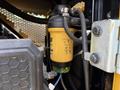 Close-up of a Caterpillar 306 fuel filter depicted with a yellow cylindrical body and various indicator symbols on its surface