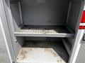 A 2009 Ford F-550 with an empty storage compartment featuring a metal shelf and a dirty floor