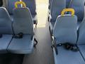 A row of blue upholstered seats in a 2013 Ford Econoline with yellow handles and seatbelts