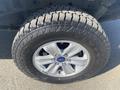 Close-up of a wheel and tire from a 2017 Ford F-150 featuring a silver alloy rim and a rugged tire tread pattern