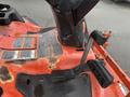 A close-up view of a 2015 Kubota F3990 mower control panel featuring levers and warning labels on the red surface
