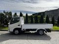 A 2004 Toyota Toyoace flatbed truck parked with an open cargo area and a white exterior