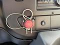 A red "FIRE" switch with a metal safety clip attached, mounted on a black control panel in a 2020 Chevrolet Express vehicle