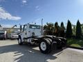 A white 2003 Freightliner M2 106 truck cab with a short chassis and large tires parked on a paved surface