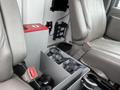 A 2016 Chevrolet Express interior showing two front seats with gray upholstery and a storage compartment with black straps between them