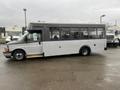 A 2017 Chevrolet Express bus in gray with large windows and a low floor design parked on a wet surface