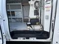 A 2008 Ford Econoline van with an open door showing interior shelving and a control box on the floor