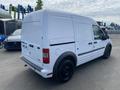 A white 2013 Ford Transit Connect van with a plain exterior and black wheels is parked, displaying its rear and side profile