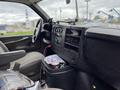The interior of a 2014 GMC Savana featuring a steering wheel dashboard and center console with papers and a drink in a cup holder