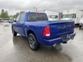 A blue 2019 RAM 1500 Classic truck with a crew cab parked with its tailgate visible showcasing the RAM logo on the rear panel and dual exhaust pipes