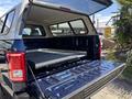 A 2015 Ford F-150 with an open tailgate and a fitted bed cover exposing a gray flat surface inside the truck bed