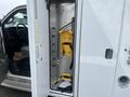 A 2016 Chevrolet Express with an open side door revealing a yellow fuel pump holder and interior access to the vehicle's storage area