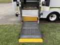 A foldable wheelchair ramp extending from the back of a 2009 Ford Econoline van
