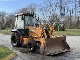 A 2005 Case 570 tractor loader with a front bucket and large rear tires parked on a driveway