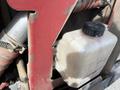 A white plastic reservoir with a black screw cap attached to a red metal frame of a 2014 Toro Groundmaster 5910