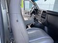 A 2023 GMC Savana interior featuring a light gray driver's seat and dashboard with control buttons and an armrest