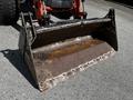 A rusted front loader attachment for a 2011 Kubota M8540D tractor with a wide, flat bucket and metal edges showing signs of wear and damage