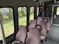 Interior of a 2014 Ford E-350 van featuring several rows of plush seats with safety straps and priority seating for persons with disabilities