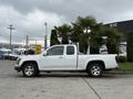 A white 2012 GMC Canyon pickup truck with a crew cab and chrome wheels parked on a concrete surface