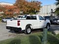 A white 2024 Chevrolet Silverado 1500 parked with the bed and tailgate visible showcasing its sleek design and modern features