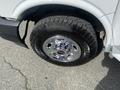 Close-up of a chrome wheel on a 2022 GMC Savana featuring a rugged tire pattern and the GMC logo visible on the hubcap