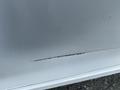 A close-up view of a scratch on the side of a 2017 Honda Accord Hybrid showing a thin line of damage on the vehicle's paint surface