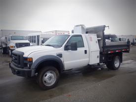 A white 2008 Ford F-550 with a flatbed and utility body is parked with its left side facing the viewer