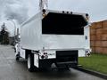 A white 2013 Ford F-650 with a large cargo box at the rear and multiple tail lights visible on the back