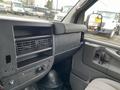 Interior dashboard of a 2012 Chevrolet Express featuring air vents control knobs and a driver's side mirror