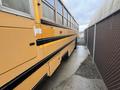 A 2009 International 3000 school bus in a yellow color parked alongside a chain-link fence with a paved pathway next to it