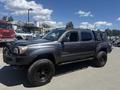 A 2010 Toyota Tacoma in gray with black wheels and a truck bed cover parked at an outdoor location