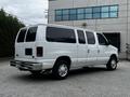 A white 2008 Ford Econoline van with a large body and multiple windows is parked, facing right with a visible rear and tailpipe
