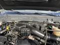 The engine bay of a 2014 Ford F-350 SD featuring a black engine cover with various hoses and components visible around it