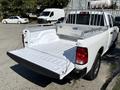 A white 2019 RAM 1500 Classic truck with an open bed and metal rack over the cabin is shown from the rear angle