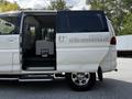 A 2003 Mitsubishi 7 Passenger Van with a sliding door open revealing the interior seating arrangement and a modern design