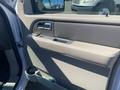 Interior door panel of a 2013 Ford Expedition with a beige color scheme featuring a handle and speaker grille
