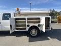 A 2015 Ford F-450 SD with open compartments on the side displaying shelving and storage space